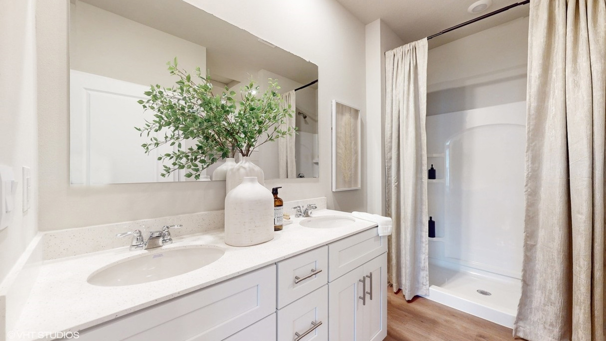 Primary bathroom with large mirror and white cabinets