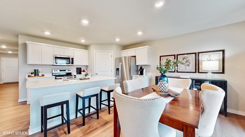 Brown dining room table with white chairs next to kitchen