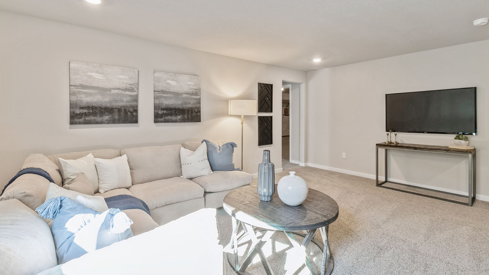 Finished basement with white sectional and small wood coffee table