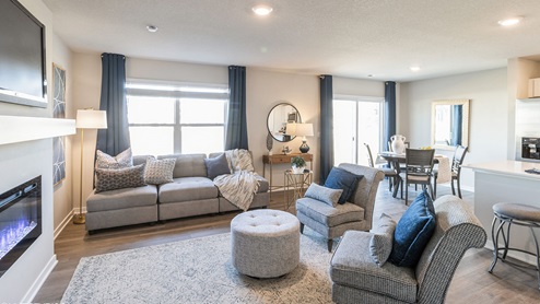 large living room with grey couch and two grey chairs next to dining area