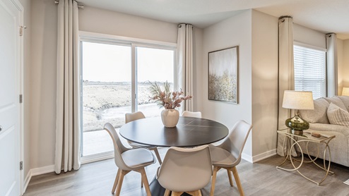 dining area with black round table and white chairs next to sliding glass doors