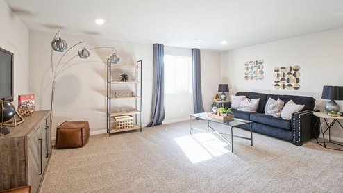 Finished basement with black couch and tv with end tables