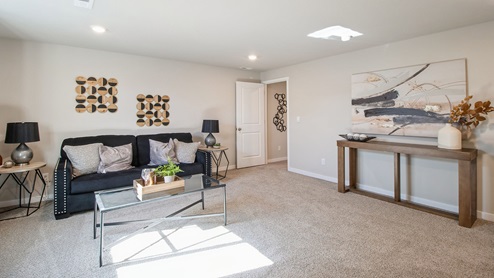 Spacious finished basement with overhead lighting and comfortable black couch