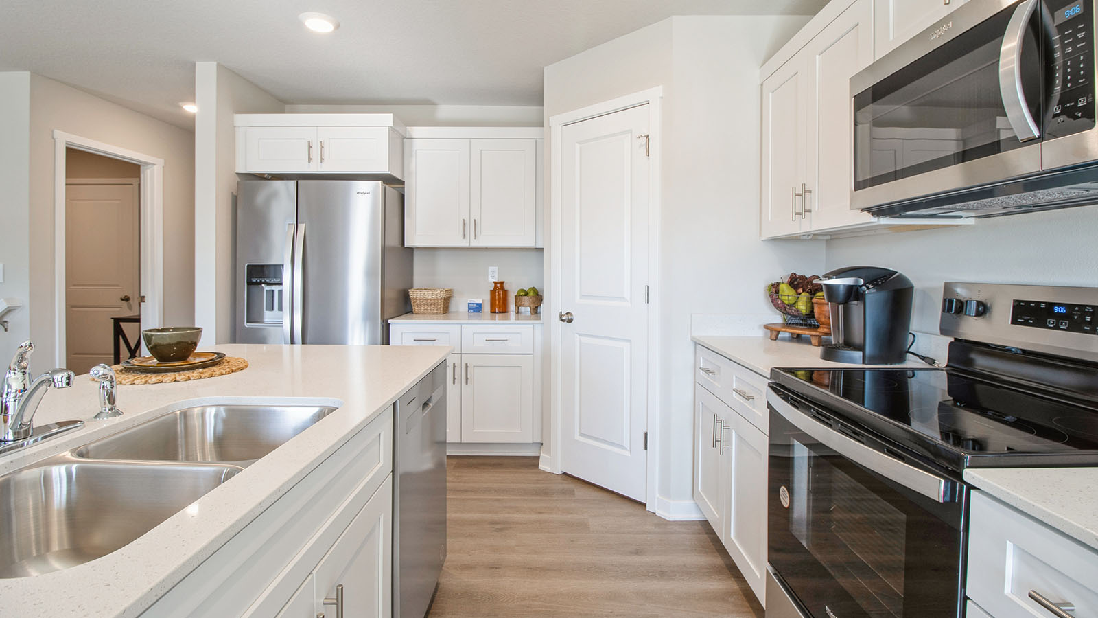 Side view of a kitchen with white cabinetry, a walk-in pantry, and stainless-steel appliances