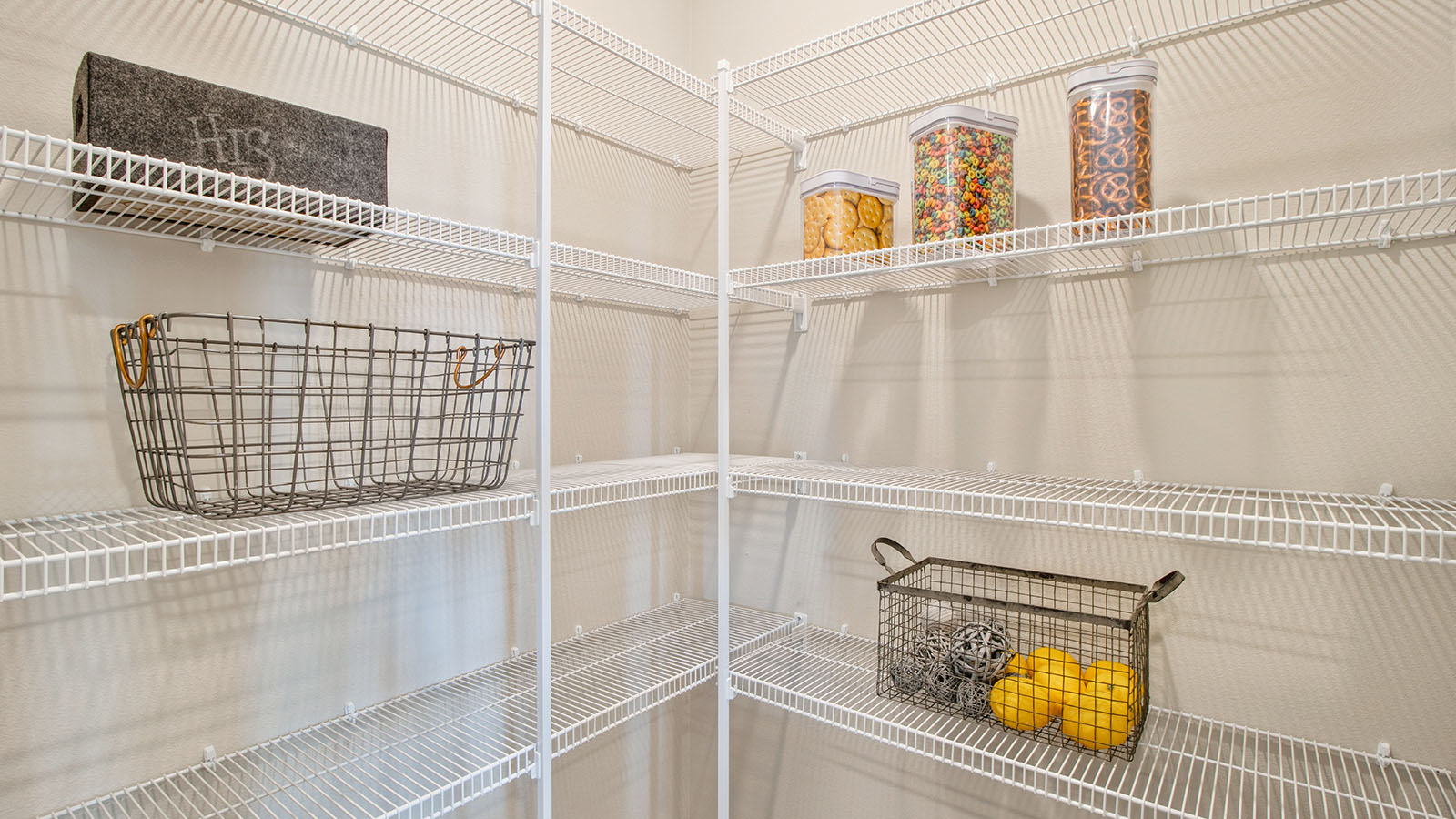Spacious walk-in pantry with white shelving and baskets