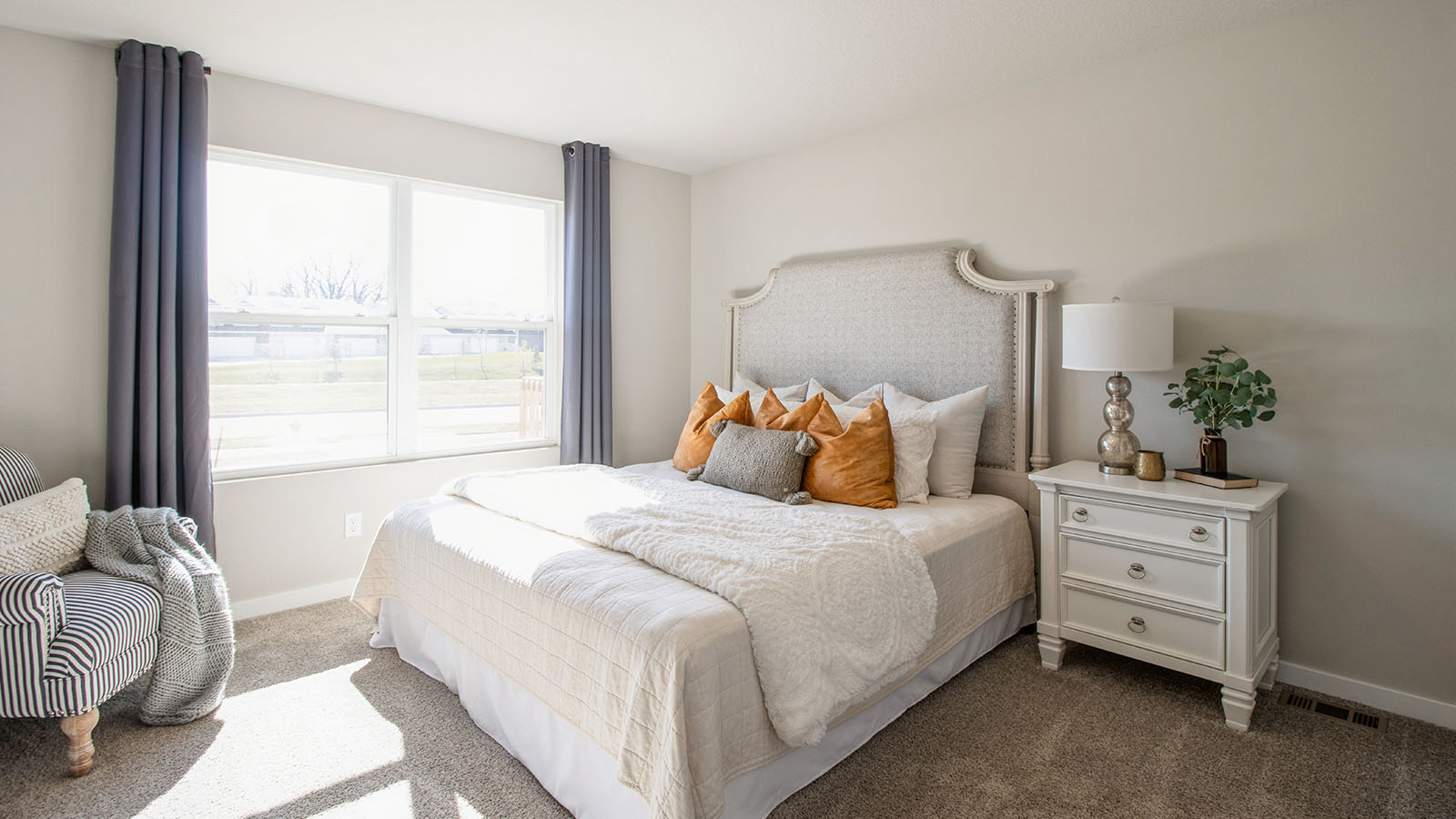 Large primary bedroom with tan bed and white nightstands and large window