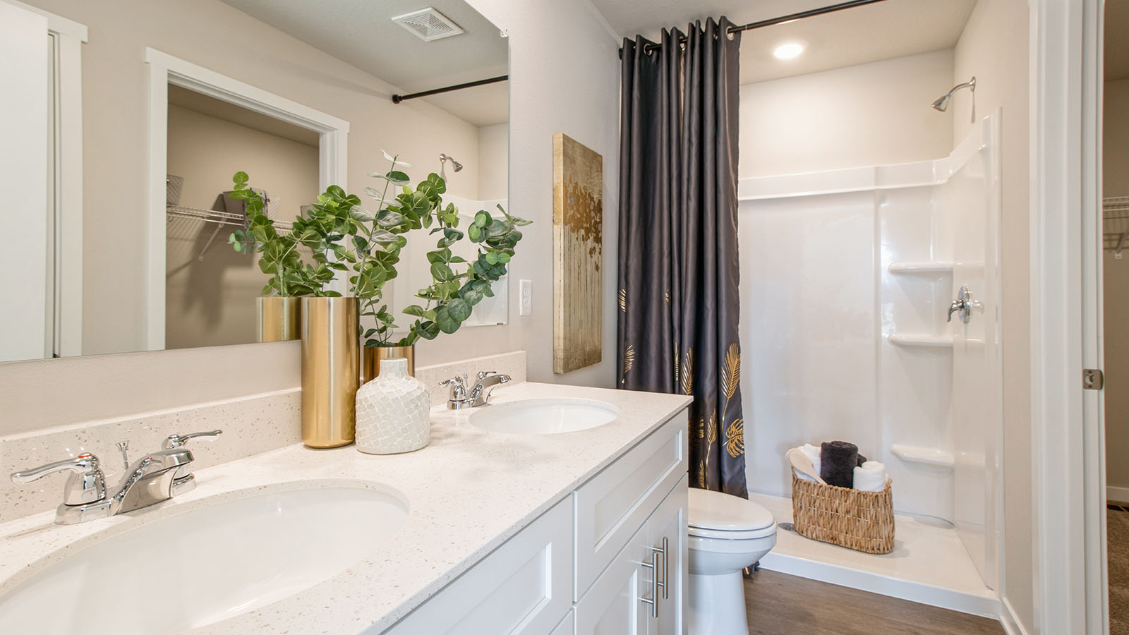 Large primary bedroom with dual sinks and white cabinetry and shower