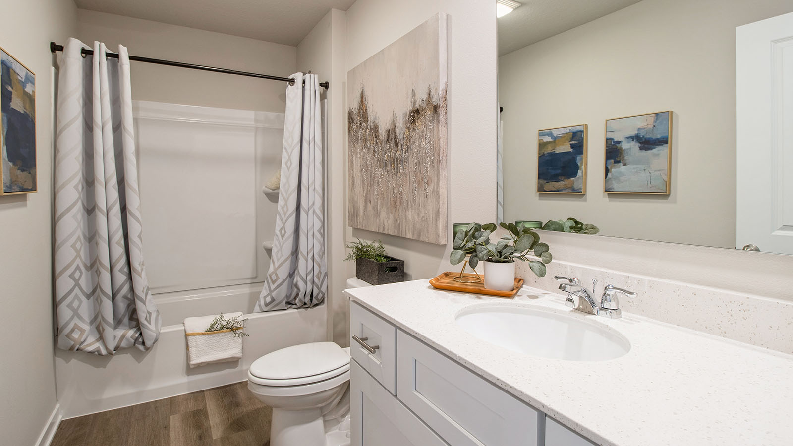 First bathroom with white cabinetry and large mirror and bathtub