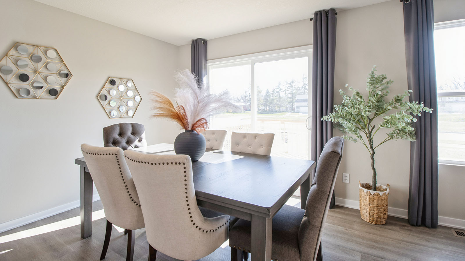 Dining area with large wood table and white chairs next to sliding glass doors