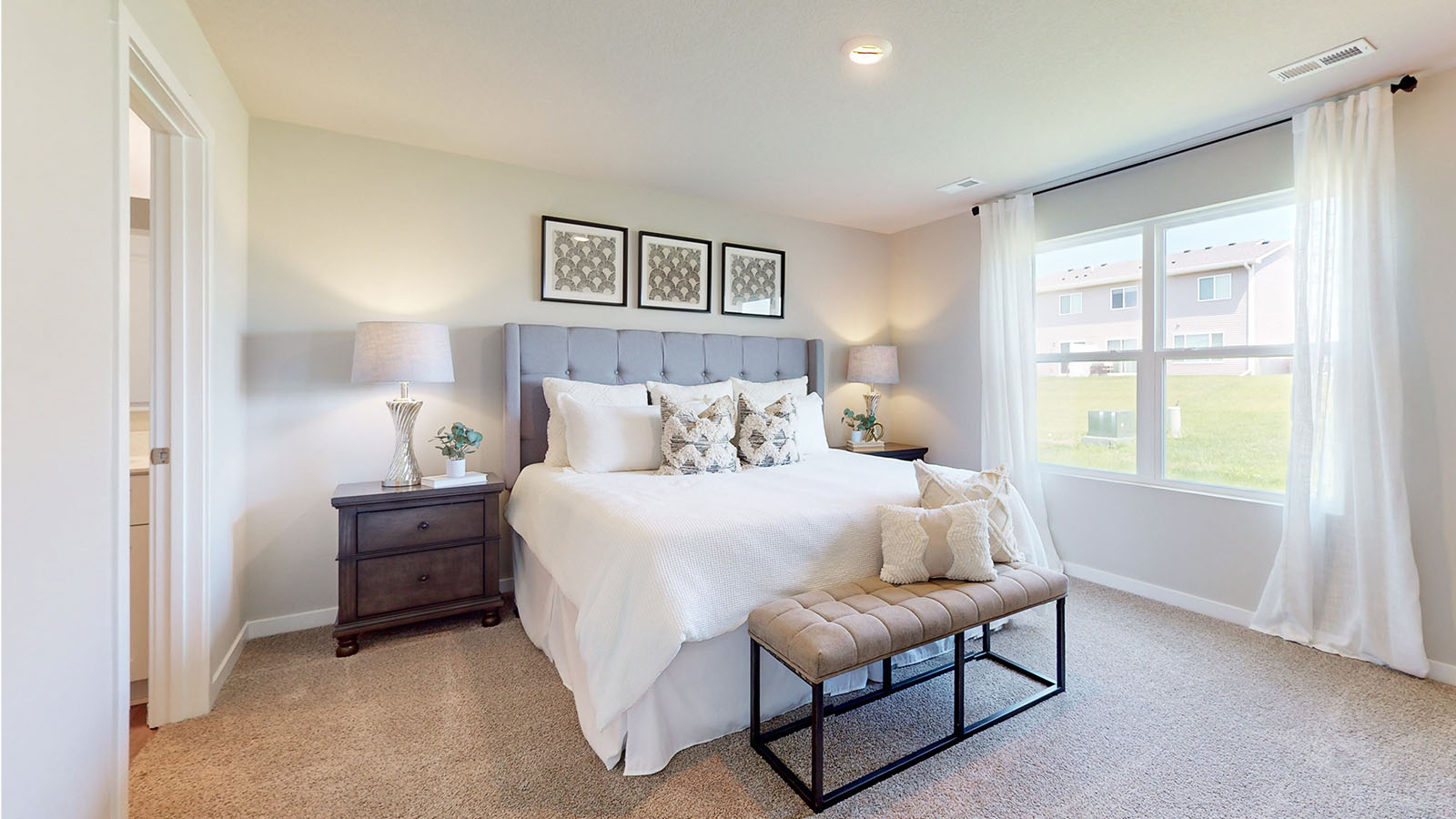 Primary bedroom with large window and carpeting.