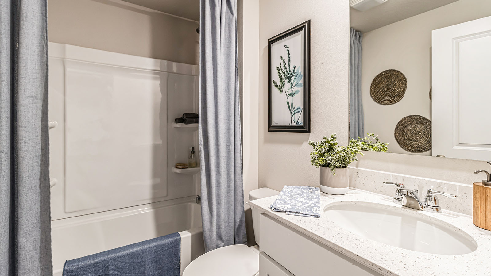 Family full bathroom with stylish vanity, mirror, cabinets, and tub-shower combo Three Lakes By D.R. Horton