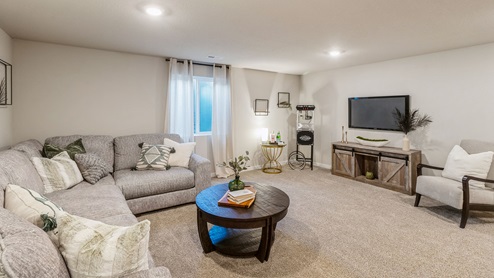 Finished basement with large grey sectional and egress window
