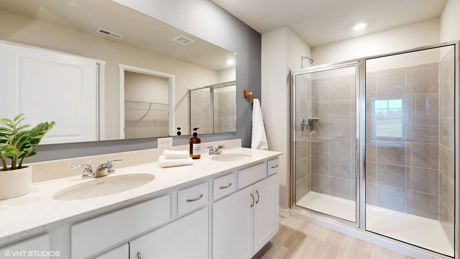 Primary bathroom with double vanity sink and shower with glass doors.