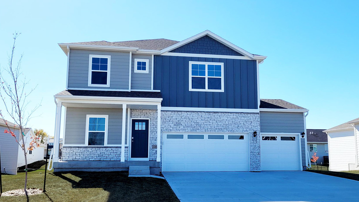 Front exterior of two story home with partial brick siding and two car garage.