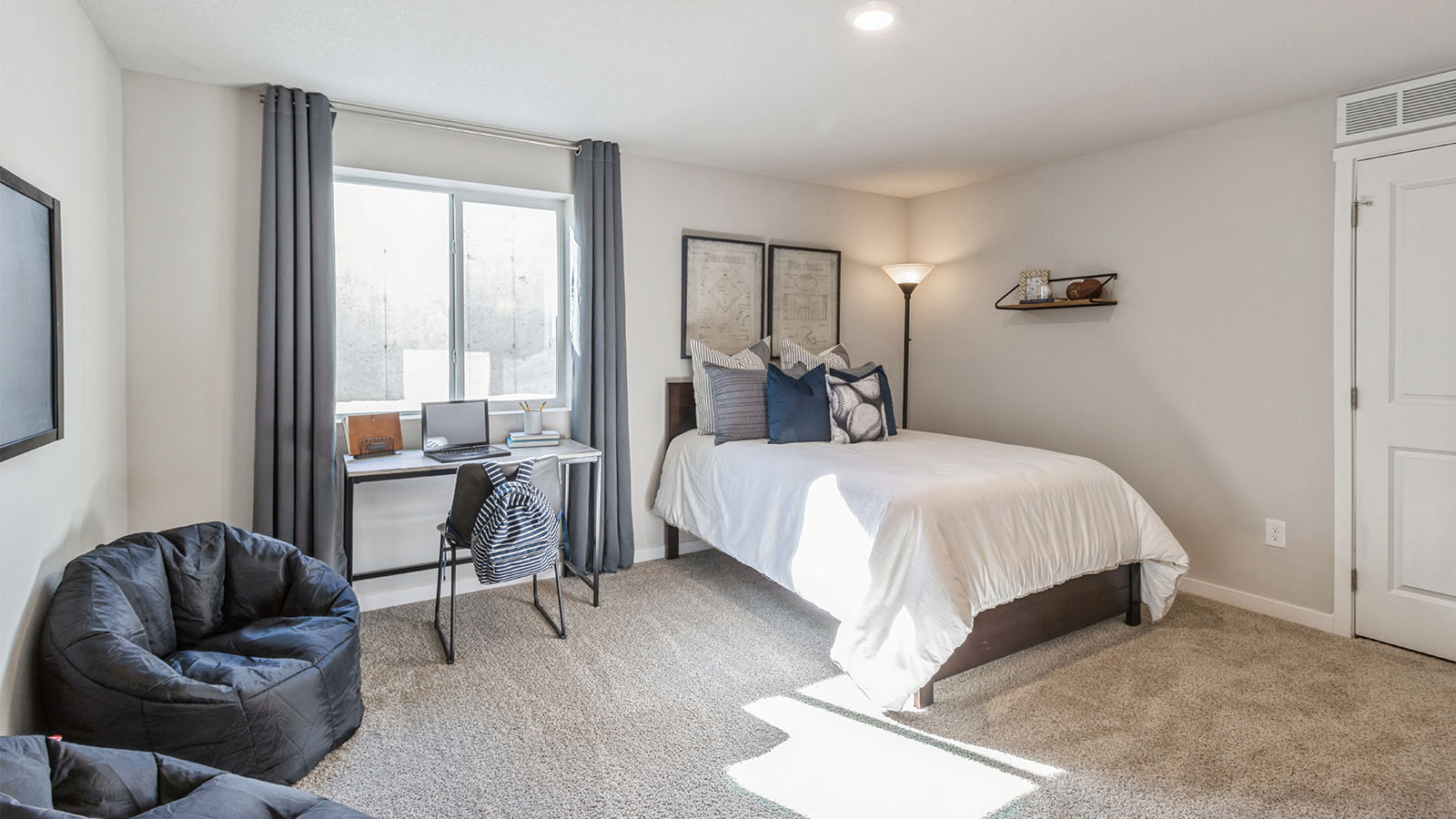 Third bedroom in the basement with white bed and egress window
