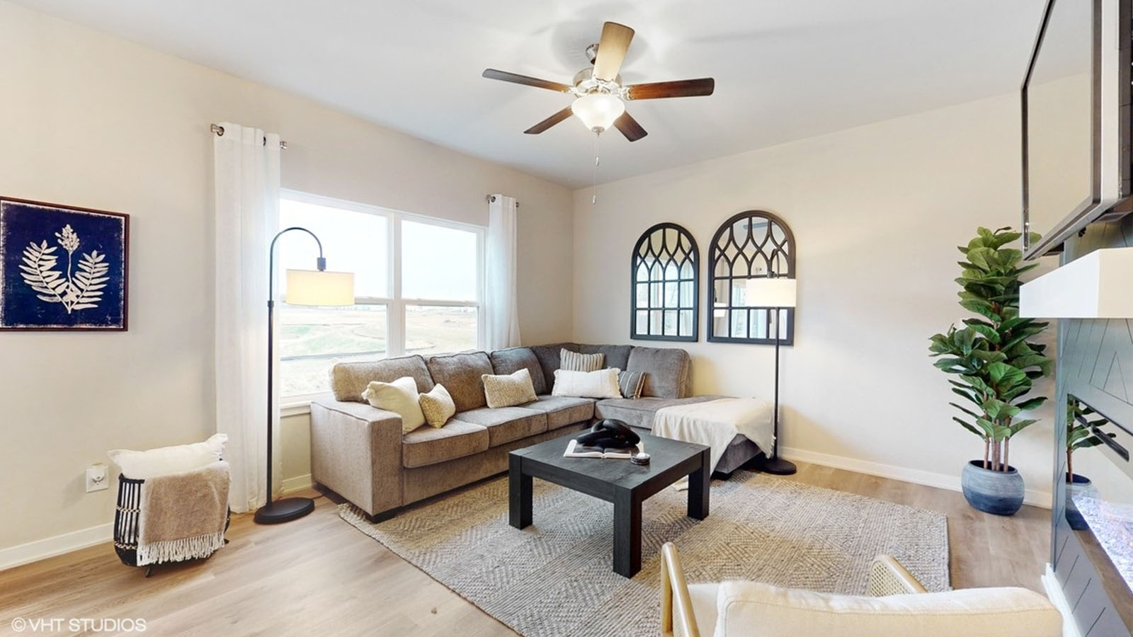 Great room, has two windows  a ceiling fan and a fireplace.