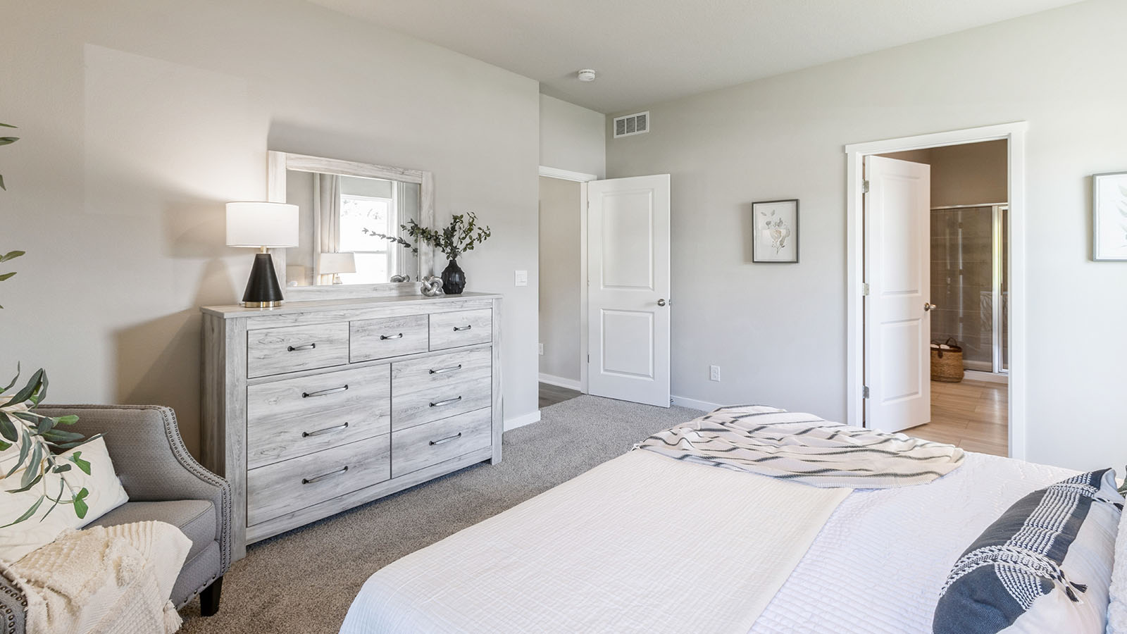 Spacious primary bedroom with white bed and white dresser
