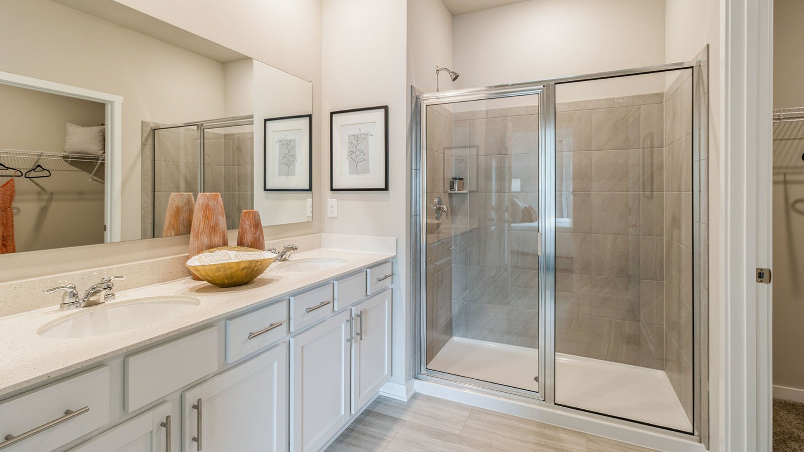 Primary bathroom with white cabinets and large mirror and tile shower