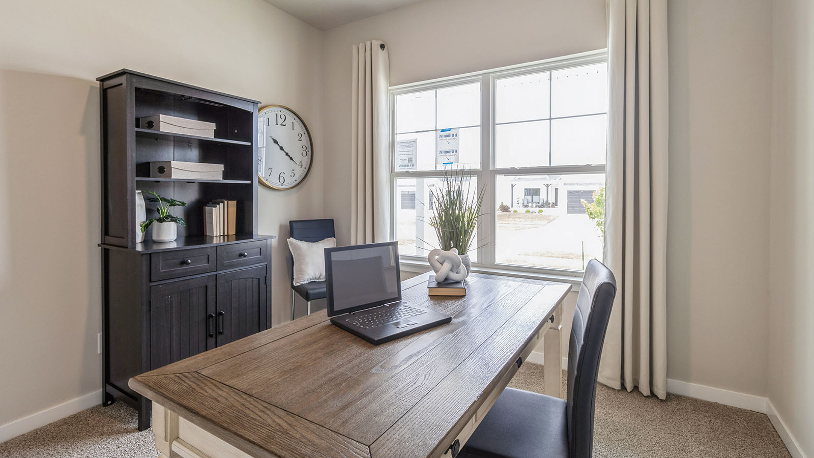 Second bedroom staged as an office with desk and black organizer next to large window