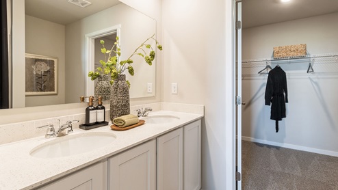Primary bedroom with large walk-in closet with white cabinets and dual sinks