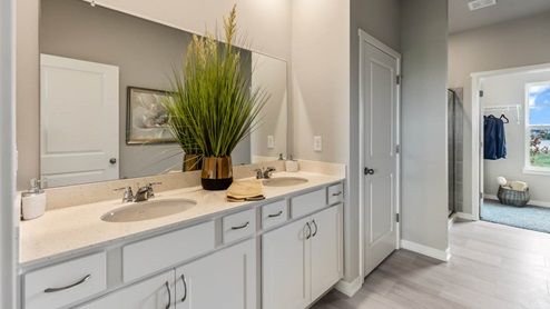 Primary bathroom with large mirror showing walk-in closet