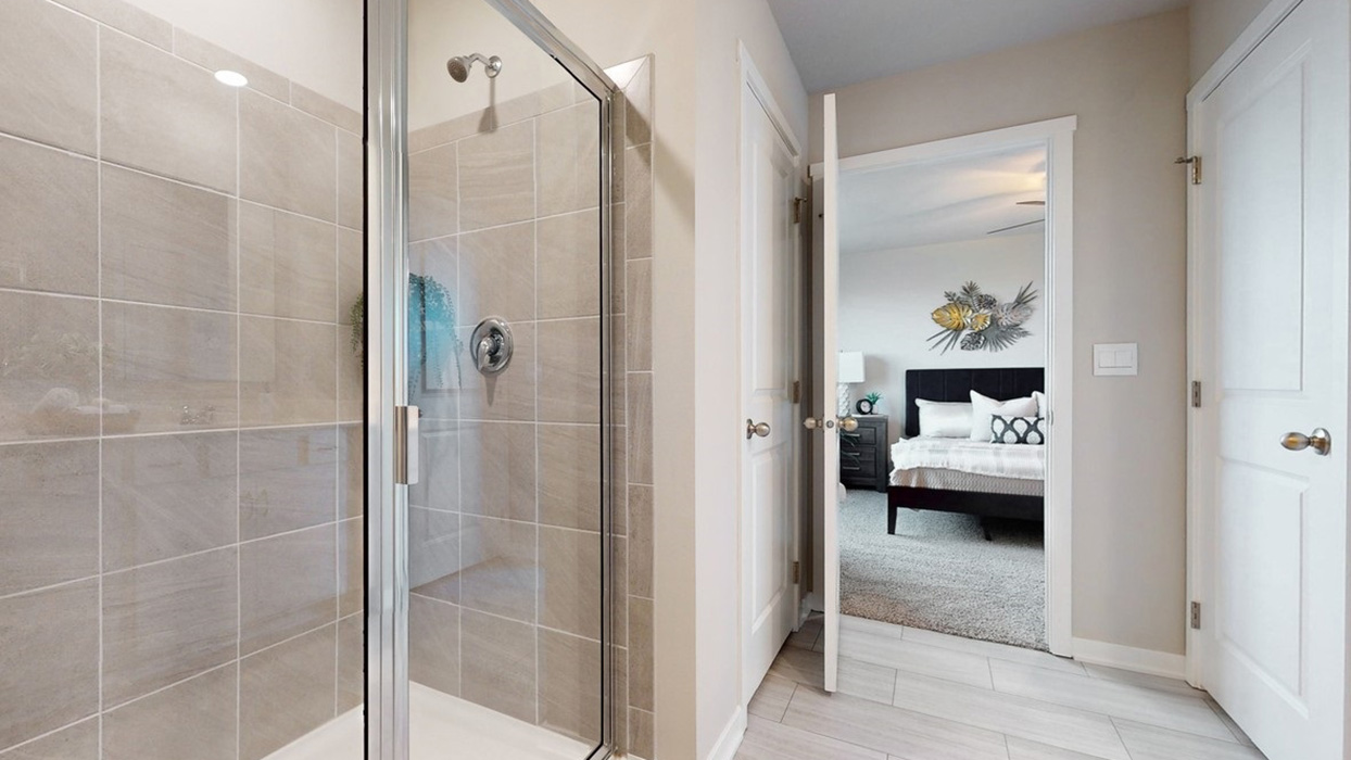 Tile shower with glass doors in primary bathroom