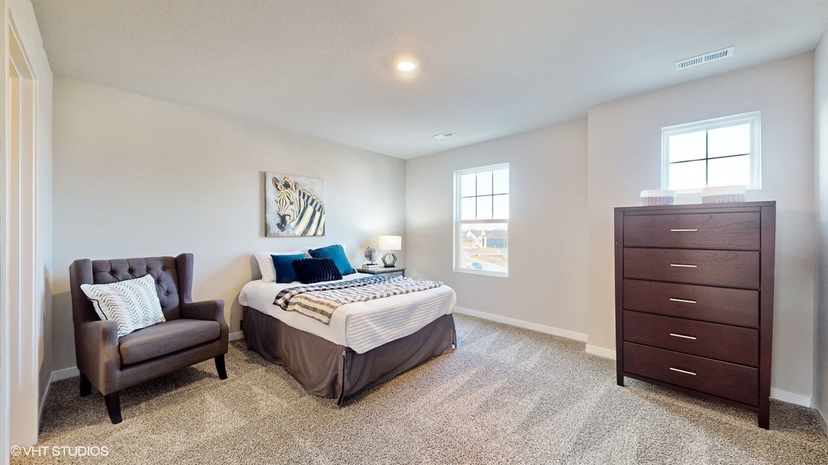 First bedroom with two windows and overhead lighting