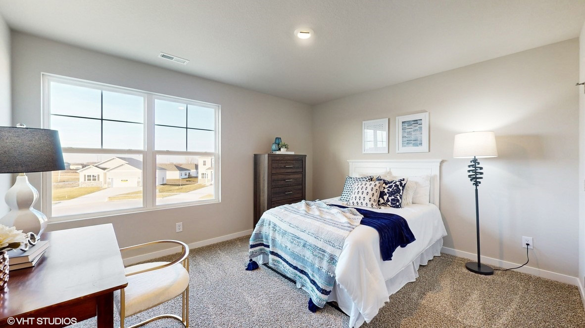 Second bedroom with large window and white bed
