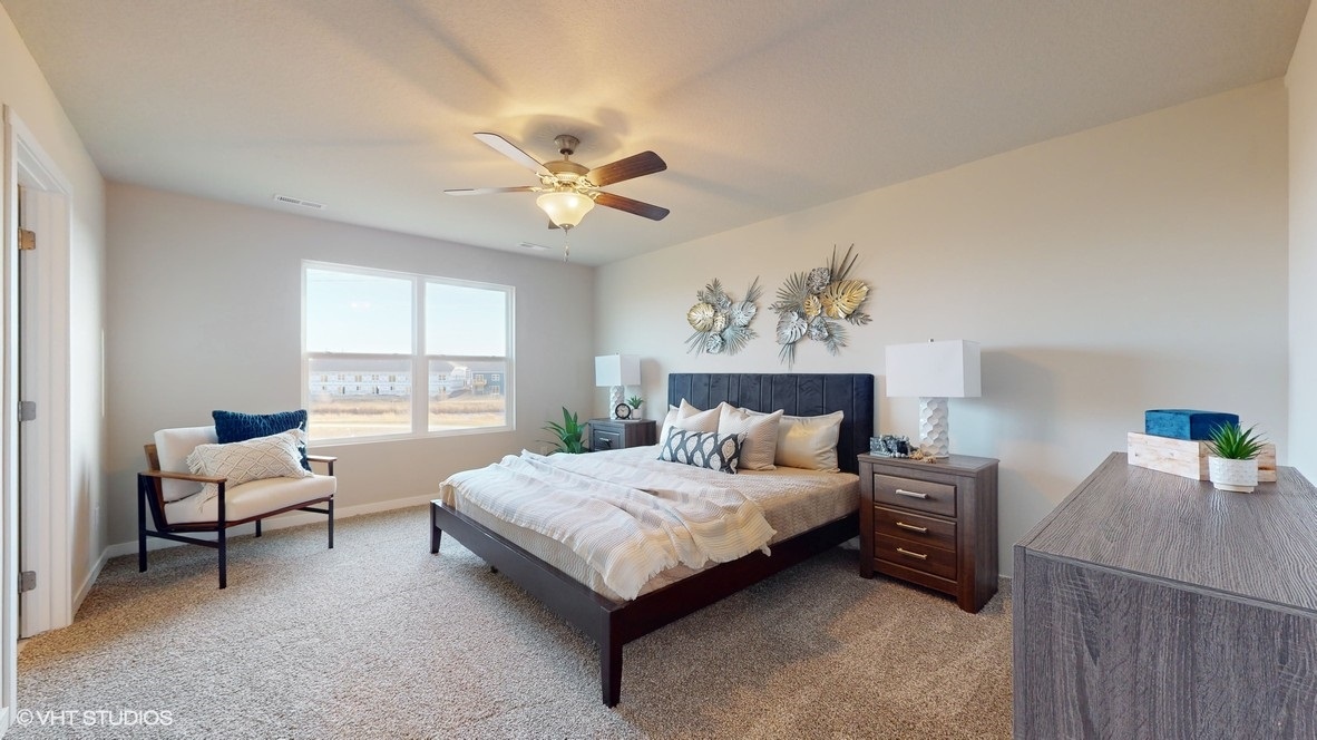 Spacious primary bedroom with white chair and brown dresser