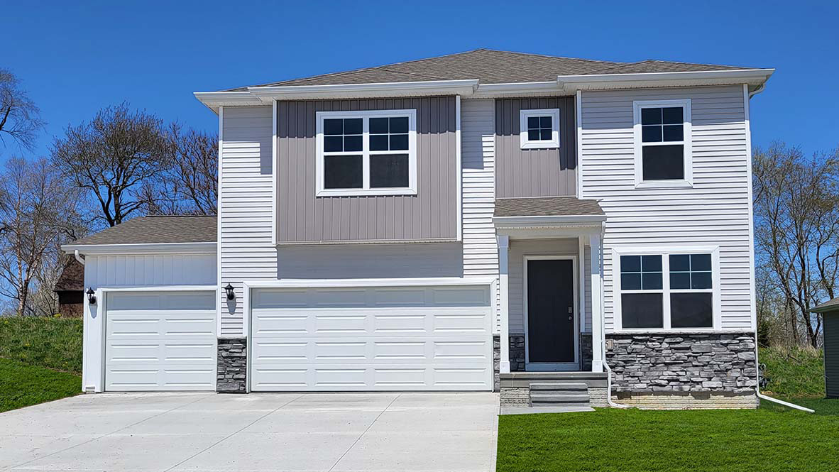 Holland exterior with grey siding, 3 car garage and stone