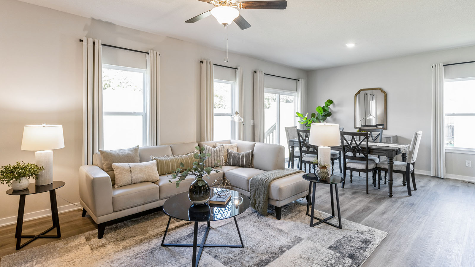 Living room with grey couch overlooking dining area with wood table