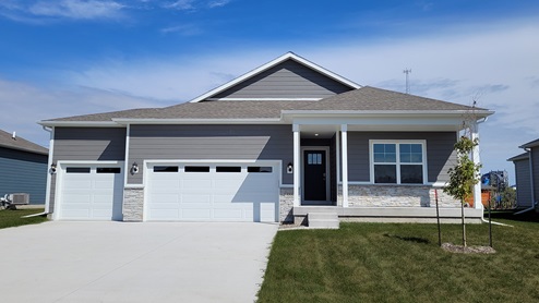 Neuville exterior with grey siding, front porch, and 3 car garage