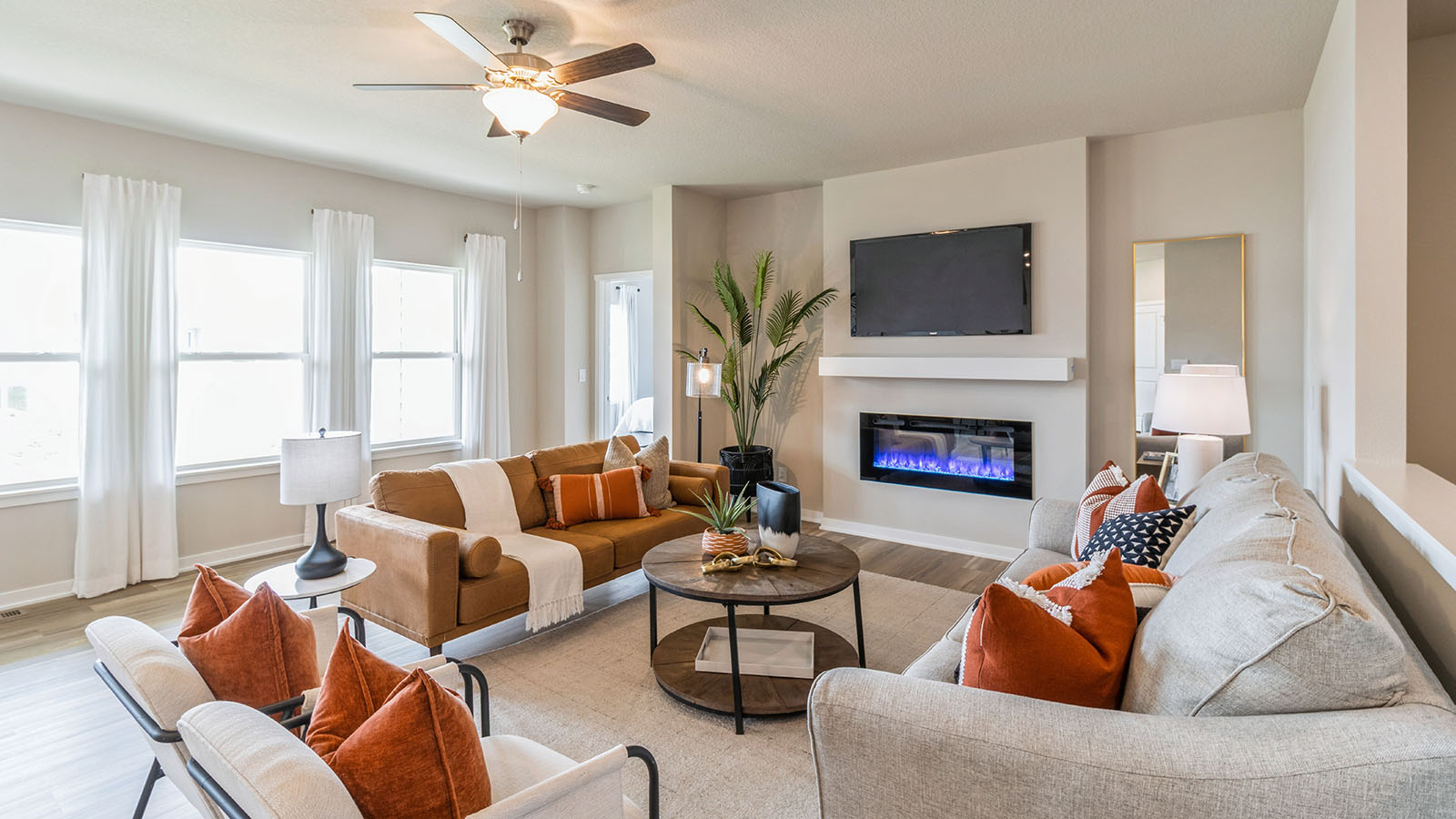 spacious living room with electric fireplace next to three windows