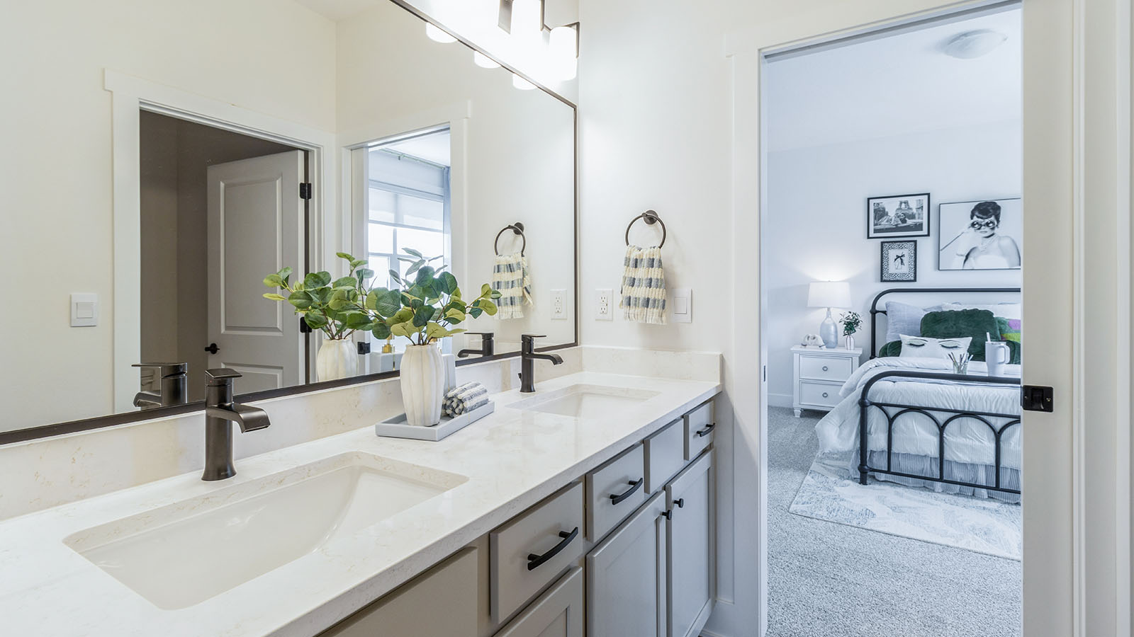 First bathroom with colored cainets and dual sinks and large framed mirror