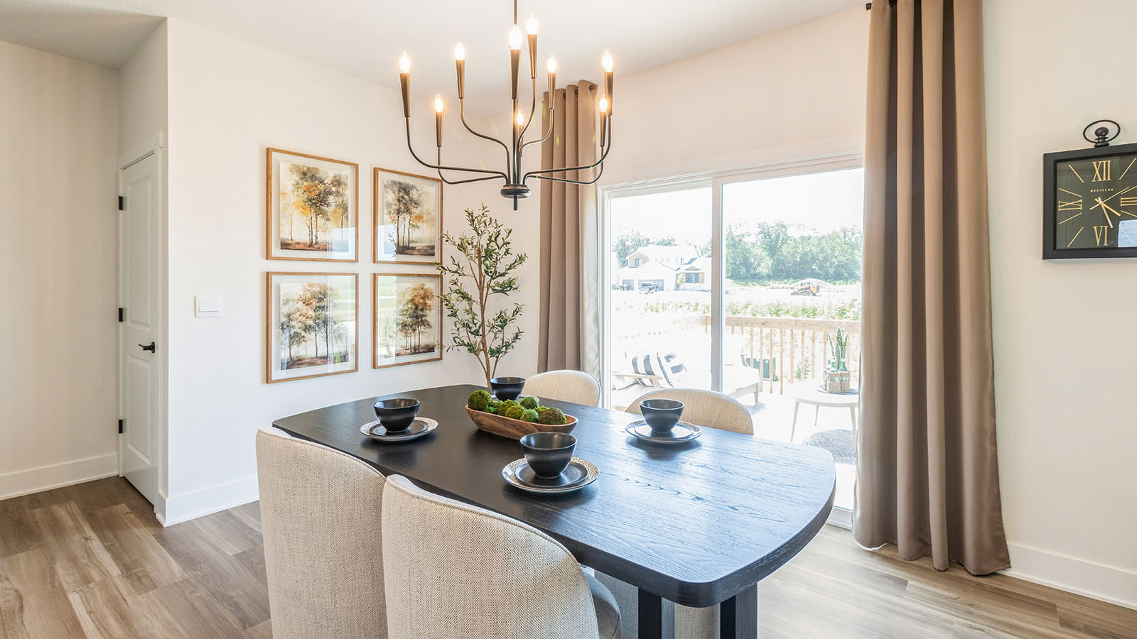 Dining area with black wood table and chandelier next to sliding glass doors