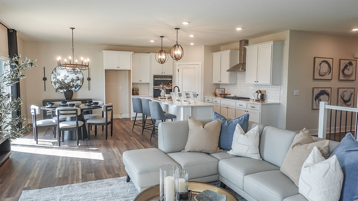 Spacious living room with brown flooring, white walls and windows