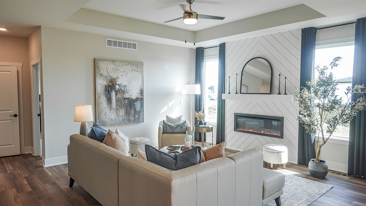 Spacious living room with brown flooring, white walls and windows