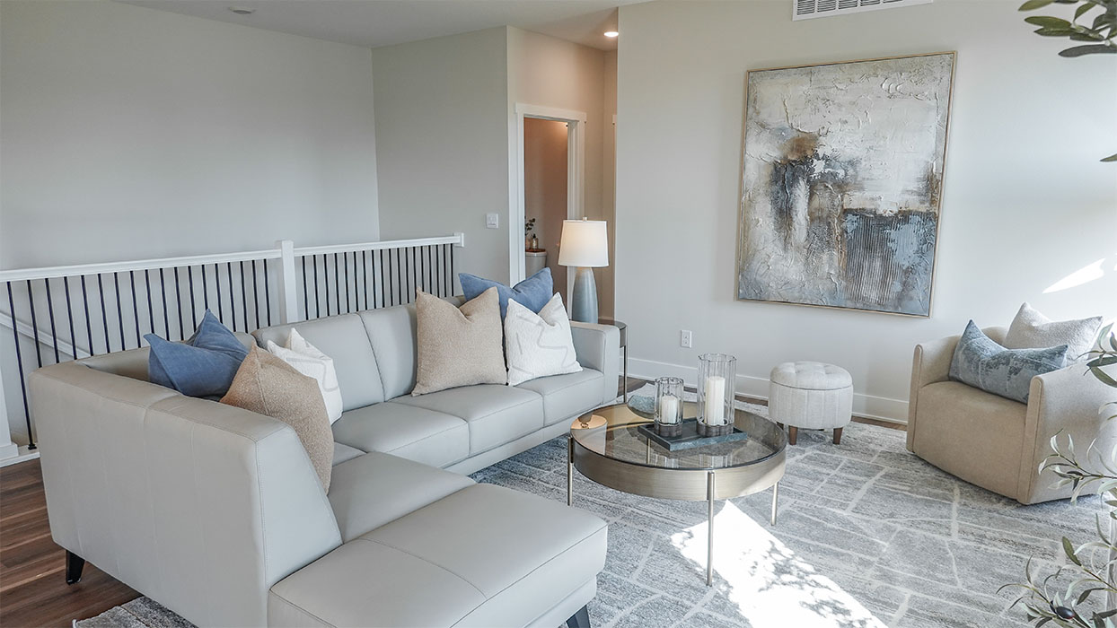Spacious living room with brown flooring, white walls and windows