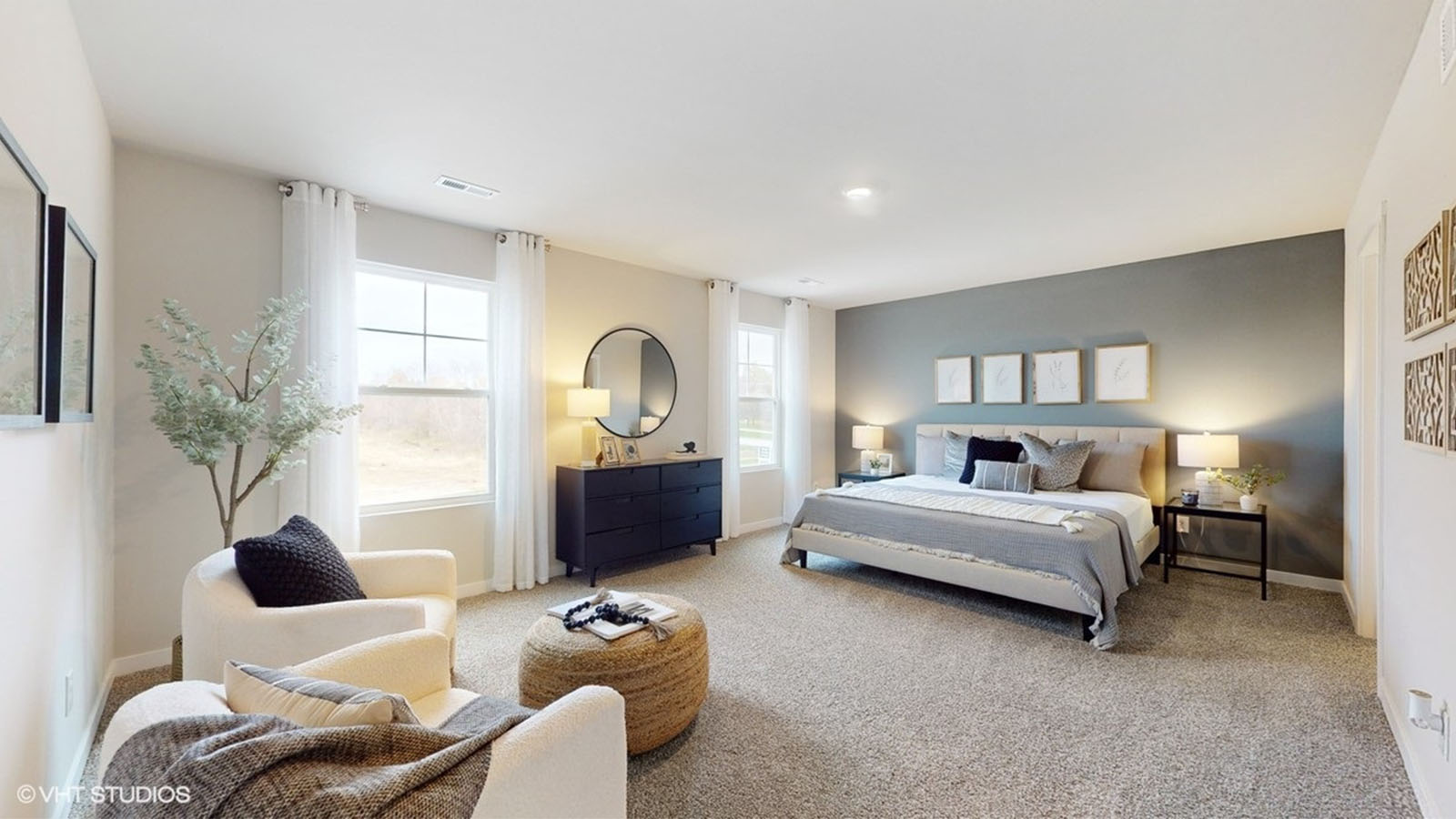Primary bedroom of the Bellhaven with a king bed, dresser and large sitting area