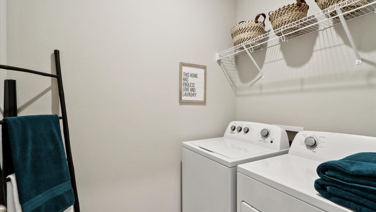 Dedicated laundry room with built-in shelving and utility connections.