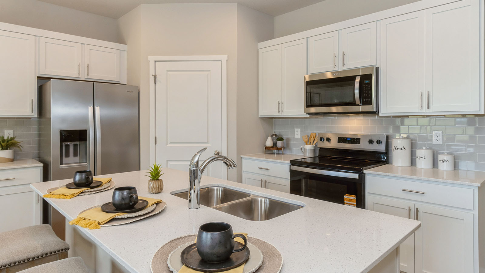 Kitchen with stainless steel appliances, quartz countertops, and white cabinetry