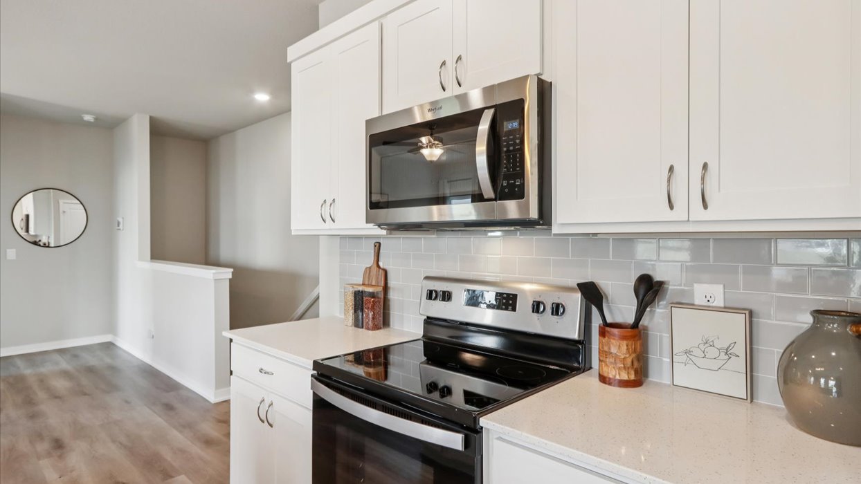Kitchen with stainless steel appliances, quartz countertops, and white cabinetry