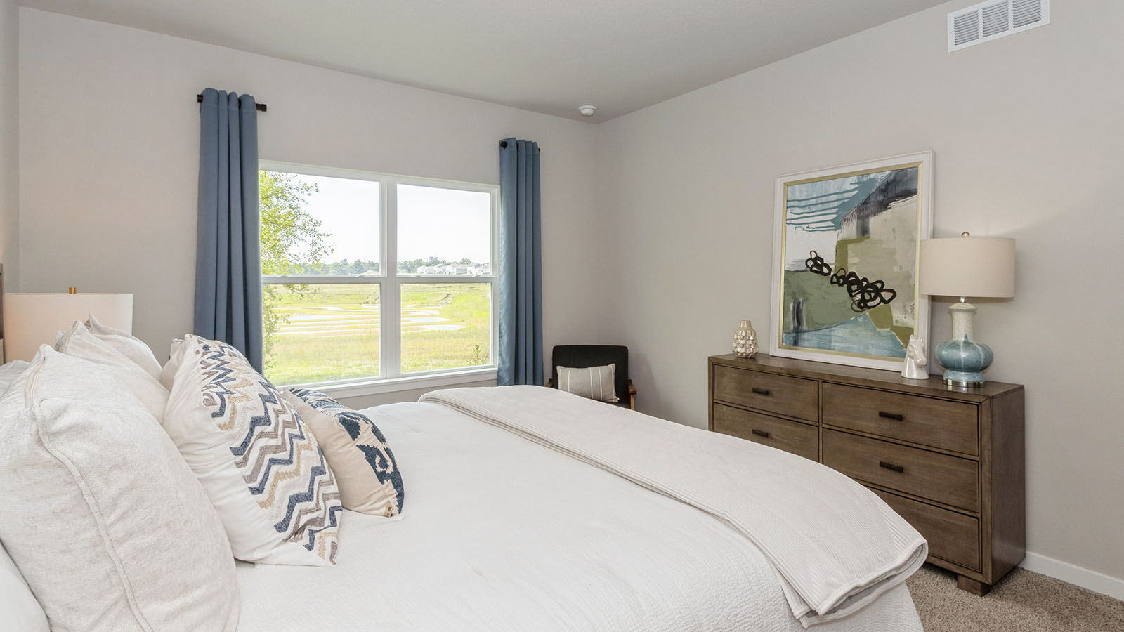 primary bedroom with large window and white bed and wood dresser