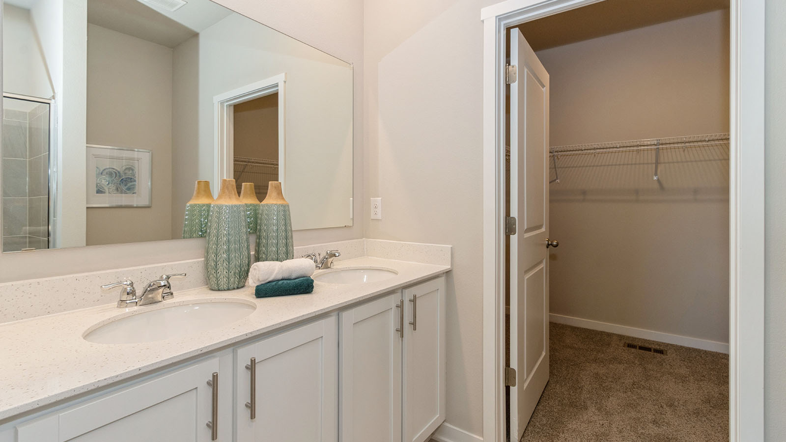 primary bathroom with dual sinks and white cabinets