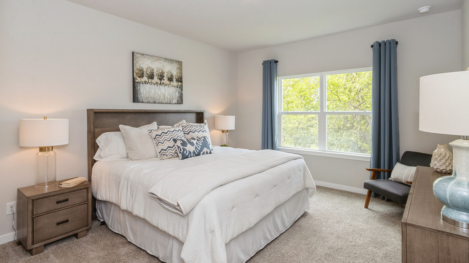 large primary bedroom with big window and white bed with wood nightstand