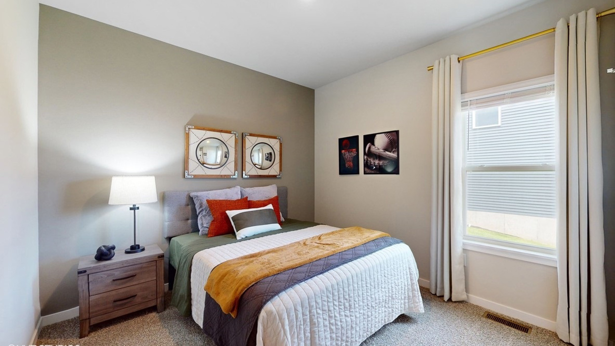 Second bedroom with a queen bed staged for a sports fan