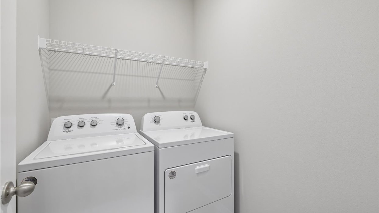 Dedicated laundry room with built-in shelving and utility connections.
