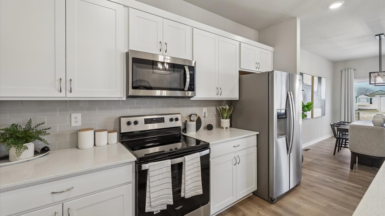 Kitchen with stainless steel appliances, quartz countertops, and white cabinetry