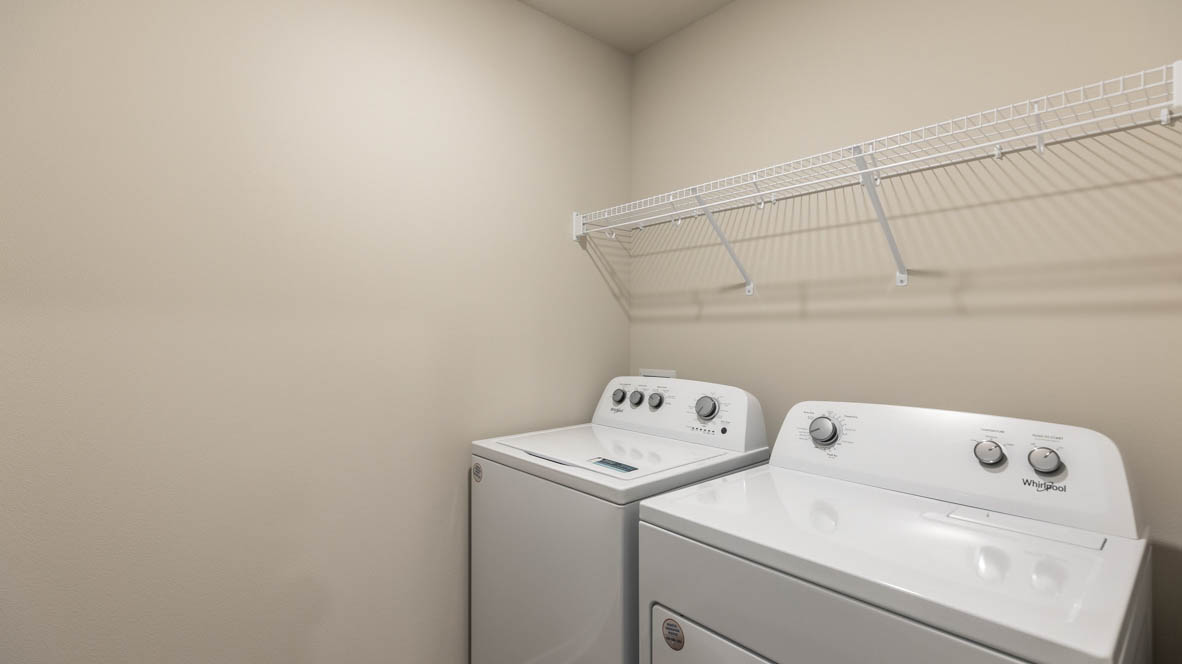 Dedicated laundry room with built-in shelving and utility connections.