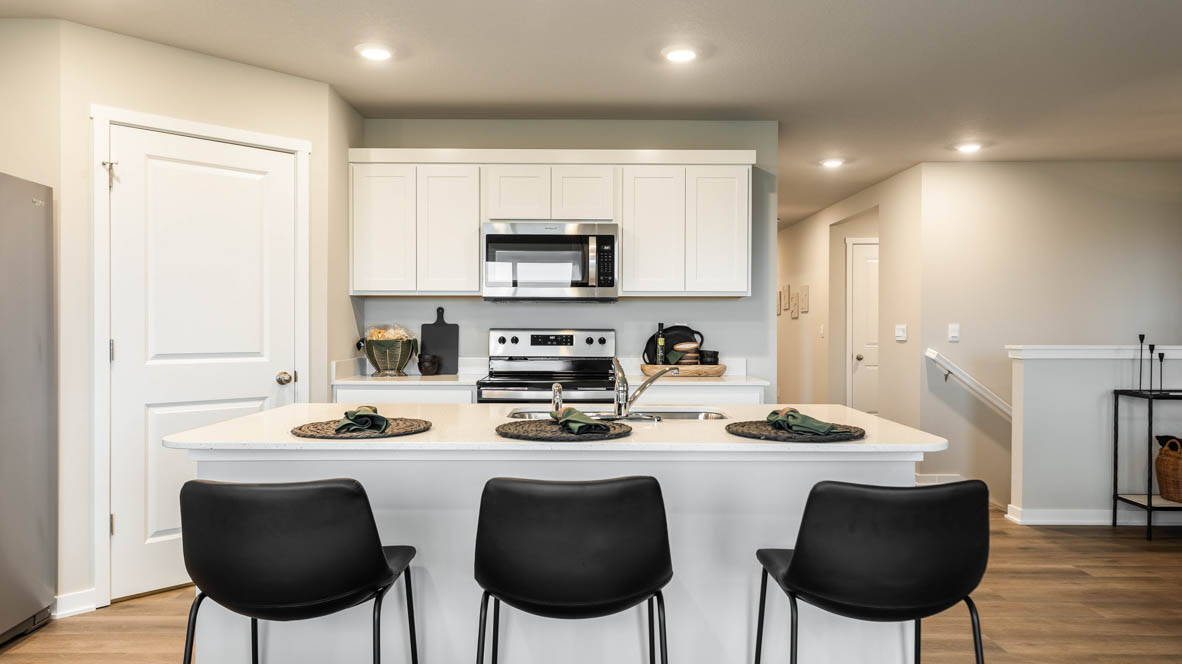 Kitchen with stainless steel appliances, quartz countertops, and white cabinetry